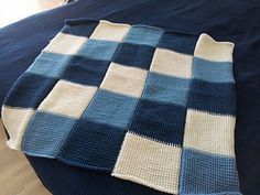 a blue and white blanket sitting on top of a bed