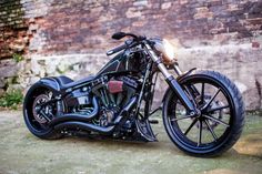 a black motorcycle parked next to a brick wall