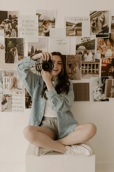 a woman sitting on top of a white box holding a camera up to her face