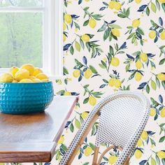 a bowl of lemons sitting on top of a wooden table next to a window