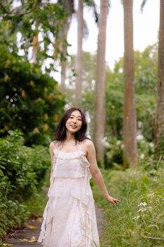 a woman in a white dress walking down a path