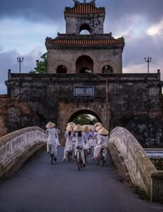 three people riding bikes across a bridge