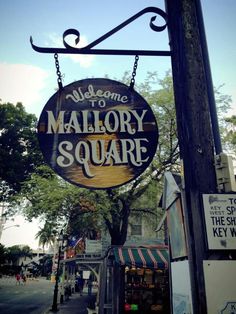 the welcome sign to mallory square is hanging from a pole