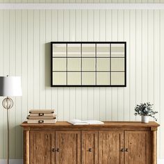 an empty room with a wooden cabinet, lamp and pictures on the wall above it