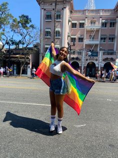 a woman holding a rainbow flag in front of a building