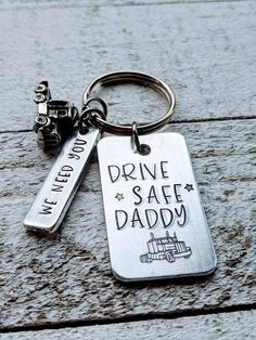 a metal keychain that says drive safe daddy and has a car charm attached to it