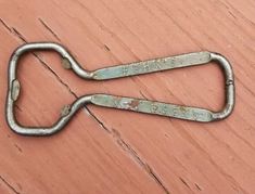 two old metal hooks are sitting on a wooden surface