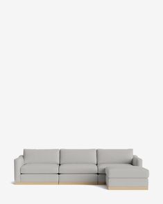 a white couch sitting on top of a wooden floor next to a gray wall in front of it