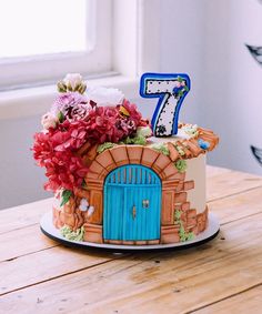 a birthday cake decorated with flowers and a number seven on the top, sitting on a wooden table