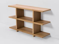 a wooden shelf against a white wall with three shelves on each side and one in the middle