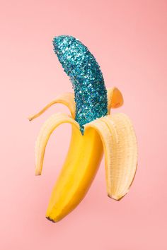 a blue glittered banana peel sticking out of it's side on a pink background