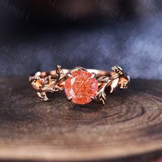 a gold ring with an orange stone in the center on top of a piece of wood