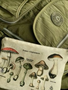 an old purse with mushrooms on it is sitting next to a green jacket and some other items