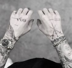 a man with tattoos holding his hands up to the camera while wearing a watch and bracelet