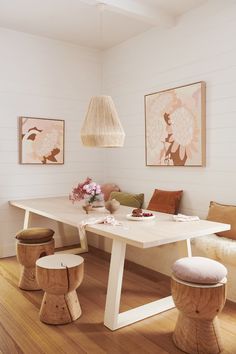 a dining room table with stools and artwork on the wall