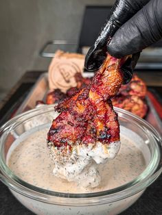 a person in black gloves is dipping something into a glass bowl with food on it