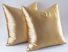 two gold pillows sitting next to each other