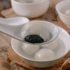 a spoon with some food in it on top of a table next to other bowls