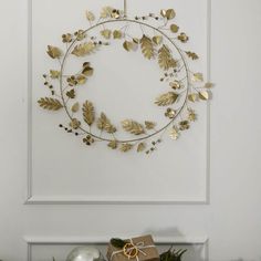 a wreath with gold leaves hanging on the wall next to christmas decorations and presents in front of it