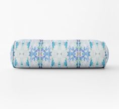 a blue and white floral print pillow on a white background, with the top rolled up