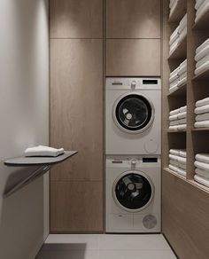 a washer and dryer in a small room with wooden shelves on the wall