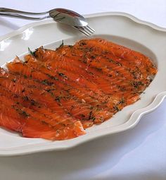 a white plate topped with sliced salmon on top of a table