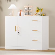 a white cabinet with yellow handles and drawers in a room next to a lamp on the wall