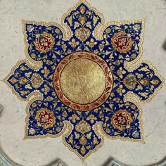 an ornate blue and gold design on the side of a white marble wall or floor