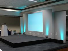 an empty stage set up for a conference with blue lights on the walls and podiums