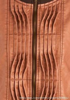 a brown jacket with zippers and pleating on the front is shown in close up