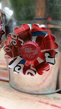 a metal bucket filled with red, white and blue soda bottle cap flowers sitting on top of a wooden table