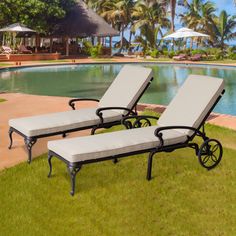 two chaise lounge chairs next to a swimming pool with palm trees in the background