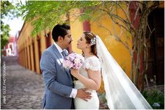 a bride and groom standing in front of a yellow building