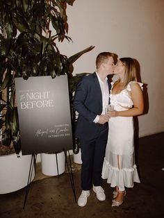 a man and woman kissing each other in front of a sign that says the night before