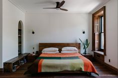 a bed sitting in a bedroom next to a window with a fan on top of it