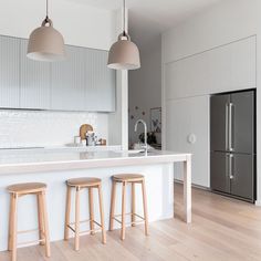 three stools sit in front of an island with white countertops and gray cabinets