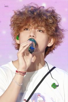 the boy is eating something with his hand and holding it up to his mouth while wearing a white t - shirt