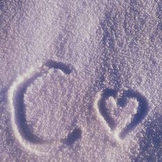 a smiley face drawn in the snow on top of a hill with two small hearts