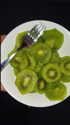 a white plate topped with sliced kiwis and a fork on top of it