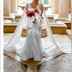 a woman in a wedding dress holding a bouquet and wearing a long veil over her head