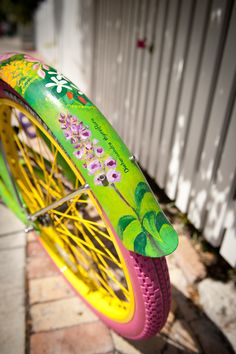 a brightly colored bicycle with flowers painted on it's front tire and spokes