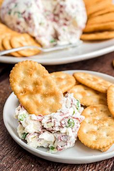 two white plates topped with crackers next to a plate of chicken salad and crackers