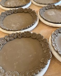 four pie pans sitting on top of a table covered in brown icing and flowers