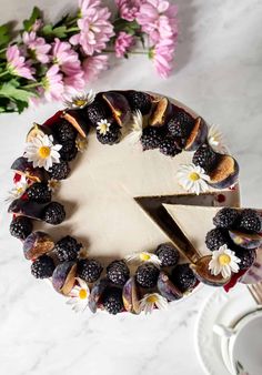 a cake is decorated with fresh berries and blackberries on the side, along with flowers