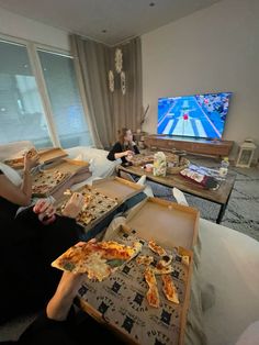 two women eating pizza in front of a flat screen tv