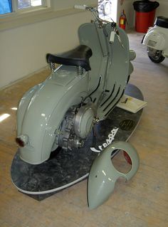 an old motor scooter is on display in a building with wood flooring