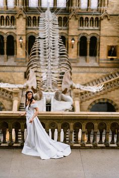 a woman in a white wedding dress standing on a balcony next to a skeleton sculpture