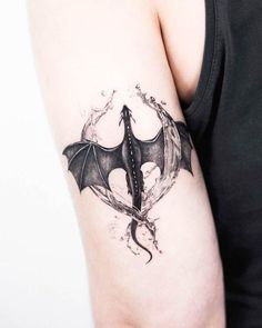 a tattoo on the arm of a woman with a bat and wings design in black ink