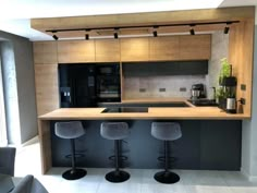 a kitchen with three stools in front of the counter