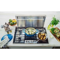 a stove top with food cooking on it and utensils sitting next to it